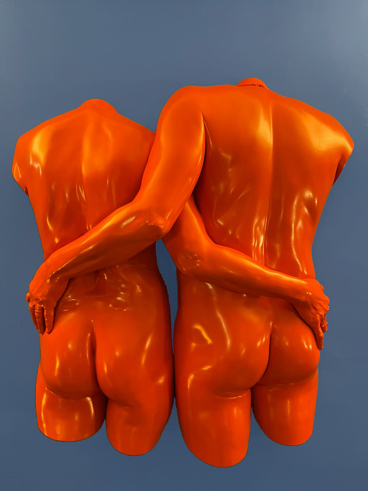 sculpture of a couple from behind in burnt orange on a blue background